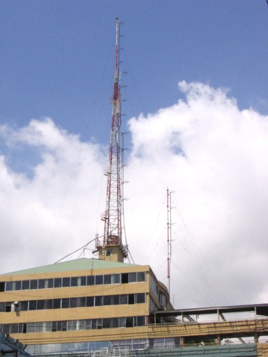 Four FM transmitting antenna arrays on two stayed masts on the roof of a commercial building