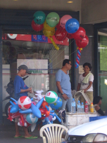 Man selling multi-coloured balloons by side of street